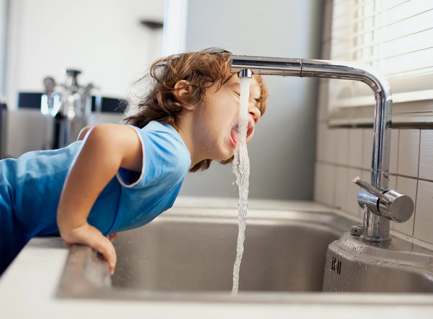 Boy drinking water from faucet